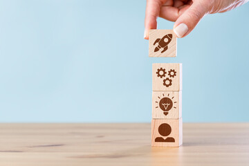 Woman hand putting wooden cube blocks on top with icons. Business strategy and action plan.