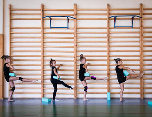 Group of girls trainees doing exercise in sports gym with sports blocks on rhythmic gymnastics...