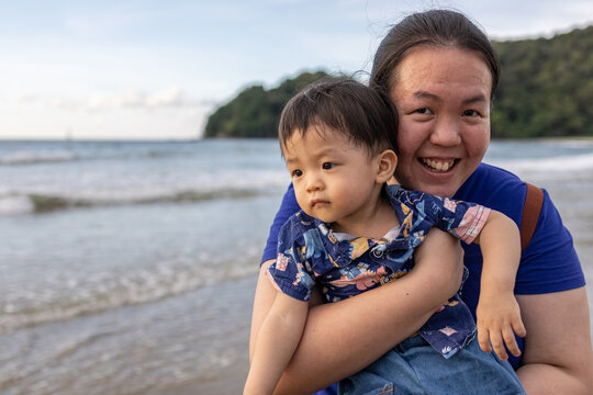 Portrait image of Happy Asian Mother and Kids enjoying family time on beautiful clean beach