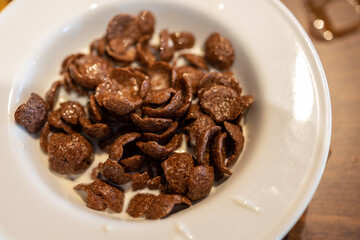 milk in bowl with chocolate cereal flakes serve on white bowl