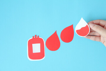 hand holding bloody bag shape made from paper on blue background, copy space, top view. blood...