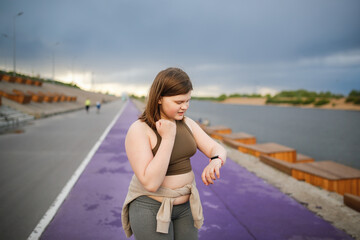 European teenage girl overweight on jog on treadmill along embankment of city, overweight and...