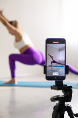 woman practicing yoga poses stretching in front of phone camera sport blogger teacher yoga online