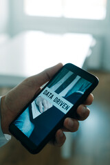 holds smartphone with the text data driven