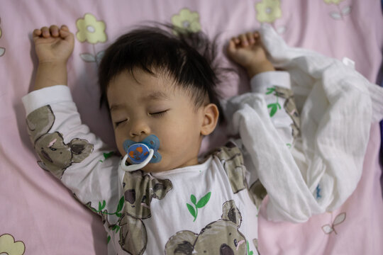 Portrait image of​ 1-2 years old​ child during sleeping with sucking pacifier.