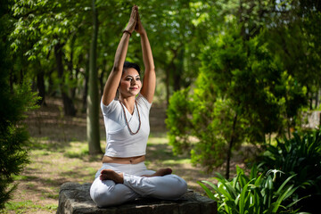 Young indian woman do yoga exercise at forest nature in summer, Asian female meditation. Mental health. Fitness. 