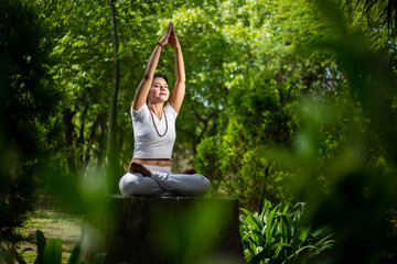 Beautiful indian woman doing yoga exercise while sitting in the green forest nature, Asian female...