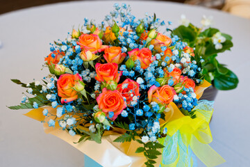 Beautiful bouquet with yellow-red roses and small blue flowers.