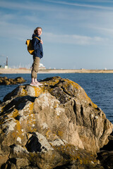 Obraz premium A female tourist with a yellow shoulder bag stands in the harbour.