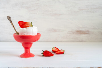 Fresh strawberries, ricotta cheese in ceramic vase on white wooden background with copy space.