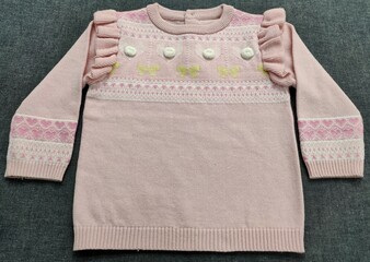 clothes isolated on white. Frill handmade multi-colour design girls warm sweater, the colour combination of a beautiful sweater has nice match on the dark grey background