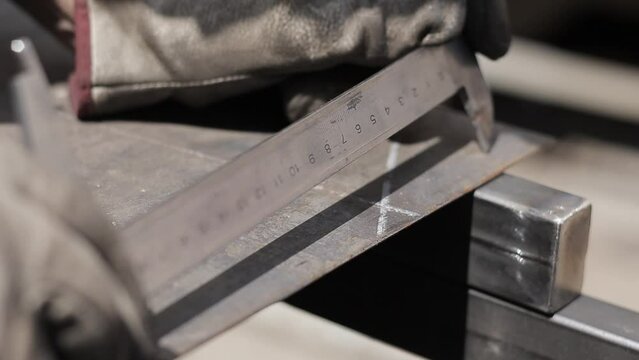 Professional male blacksmith forming red hot metal on an anvil in interior blacksmith workshop.