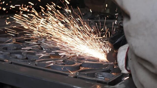 Professional male blacksmith forming red hot metal on an anvil in interior blacksmith workshop.