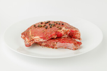Raw meat for steak in a marinade on a white plate.