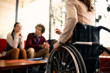 Unrecognizable businesswoman with disability talks to her colleagues in the office.
