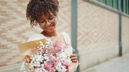 young woman in glasses walks with a bouquet of flowers along the street of the old city and listens to music in wireless headphones