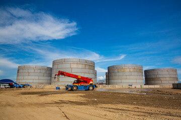 Obraz premium Constuction of an oil derrick crane, big oil tanks