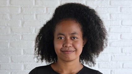 Young charming woman of multicultural race stands near a bright wall. She looks amazing, thick...