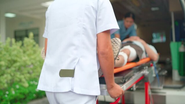 Staff man and emergency team bring patient lie on stretcher bed into ambulance van and other staff help to support the patient.