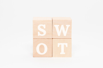 SWOTの文字。4つの木製ブロックに書かれている。白い文字。白い背景。