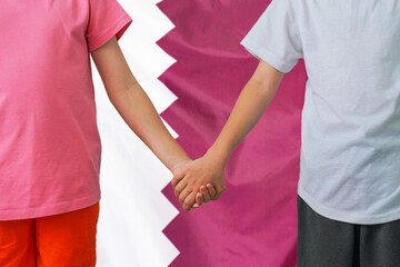 Two children joined hands on flag Qatar background. Boy and girl joined hands on background flag of Qatar. Concept of family and parenting in Qatar