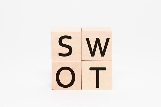 SWOTの文字。4つの積み上げられた木製ブロックに書かれている。黒い文字。白い背景。
