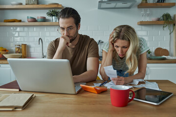 Frustrated young couple going over home finances at the domestic kitchen