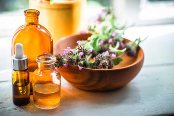 Apothecary bottles near raw materials from fresh flowering Clinopodium vulgare, Wild basil,...