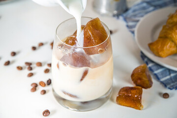 Cold coffee cocktail with frozen coffee espresso ice cubes and milk. Summer cool refreshment latte drink on white background copy space