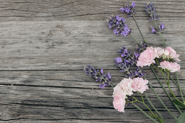 Bouquet of lavender flowers and little pink roses on old wooden table background. Decorative floral...