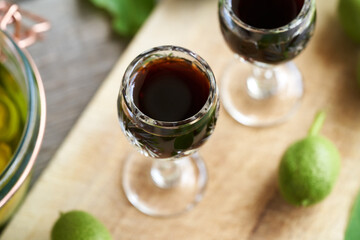 A glass of homemade nut liqueur with unripe walnuts