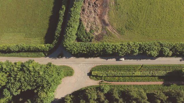 Aerial drone shot of a single car driving along a quiet country lane