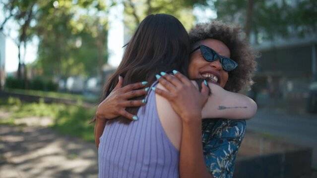 Two cheerful multiethnic women hugging outdoors