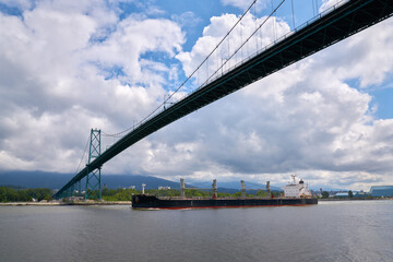 Freighter Departing Vancouver Lion's Gate Bridge. A freighter departs Burrard Inlet and downtown Vancouver under the Lion’s Gate bridge.

