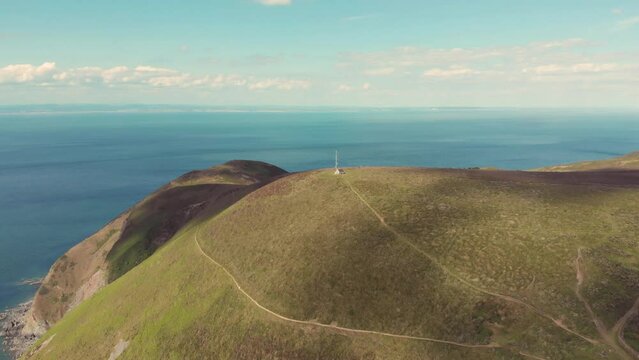 Aerial drone shot of single isolated house on a remote cliff overlooking the blue ocean