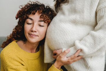 Gay female couple having tender moment listening her pregnant wife baby belly - Lgbt Lesbian family love