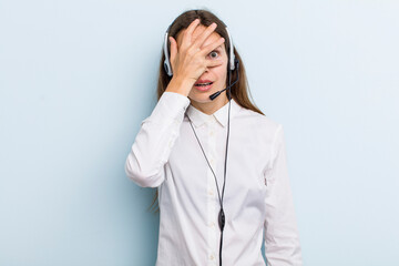 young adult woman looking shocked, scared or terrified, covering face with hand. telemarketer...