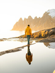Photographer walking alone in Norway traveling solo outdoor active healthy lifestyle sustainable tourism Okshornan peaks view Senja islands. Tungeneset beautiful reflections of the Mountains