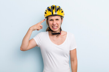 blonde young adult woman feeling confused and puzzled, showing you are insane. bike helmet concept
