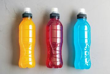 Flat lay shot of three bottles of isotonic drink on a grey concrete background