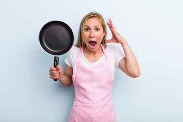 blonde young adult woman screaming with hands up in the air. chef concept