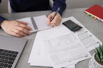 Businessman sitting at a table in office writing notes down on a spiral notepad. Business man doing...