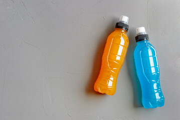 Flat lay shot of three bottles of isotonic drink on a grey concrete background with a copy space on...