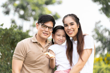 Obraz premium Asian girl running on the lawn in a public garden Do activities together with your family in a fun and joyful way. There is a father and mother taking care of them closely.