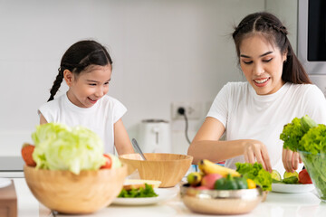 Obraz na płótnie Canvas Asian girl learning to cook with her mother. Do activities together with your family in a fun and joyful way. There is a mother who takes care of closely
