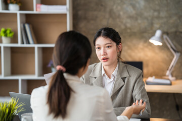 Fototapeta premium Two Businesswomen Having Informal Meeting In Modern Office, mentor helping apprentice explain corporate program, support teamwork concept.