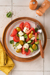 Greek salad. Fresh Greek salad with fresh vegetables, tomato, cucumber, green olives and feta cheese on old grey concrete table background. Top view.