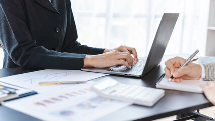 Close up two woman hands working together with laptop and calculator to calculate and analysis business financial data.