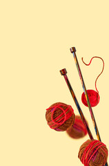 balls of thread and knitting wooden needles on a yellow background, selective focus, copy space