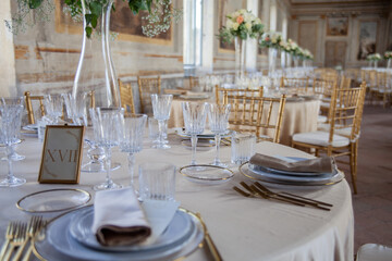 Hall of an ancient castle with catering for wedding events. The tables are set up with fine plates, glasses and cutlery